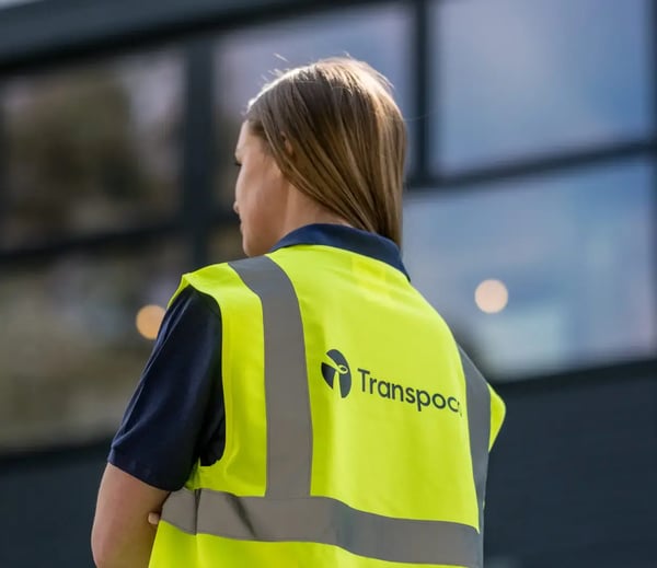 Transpoco employee in a high-vis jacket looking towards the company's offices