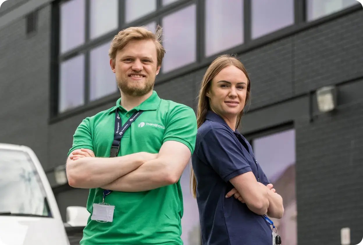 Two smiling Transpoco employees standing shoulder-to-shoulder with their arms folded