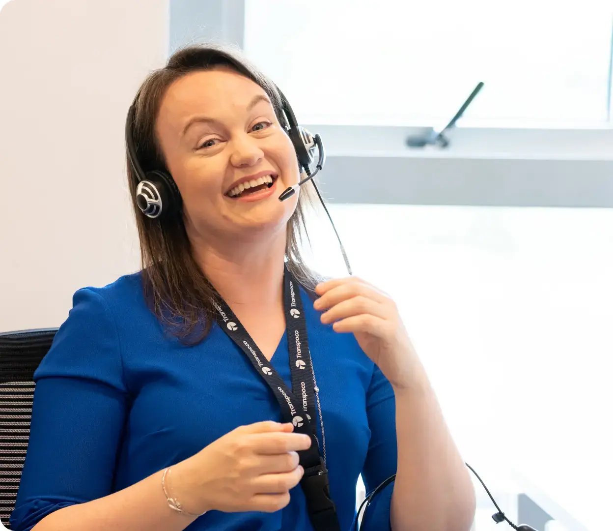 Smiling Transpoco employee in a blue shirt using a telephone headset