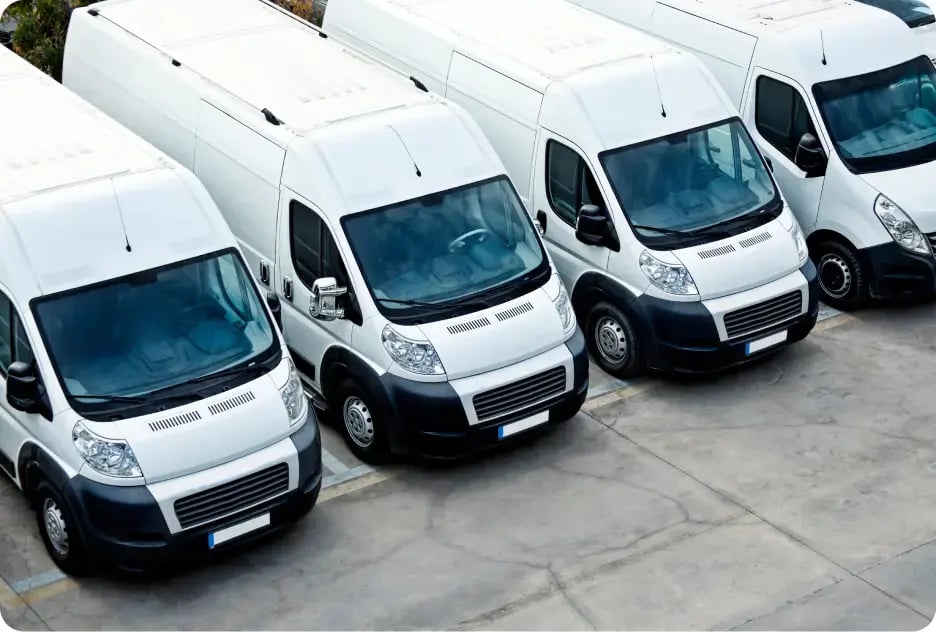 A row of white vans in a parking lot