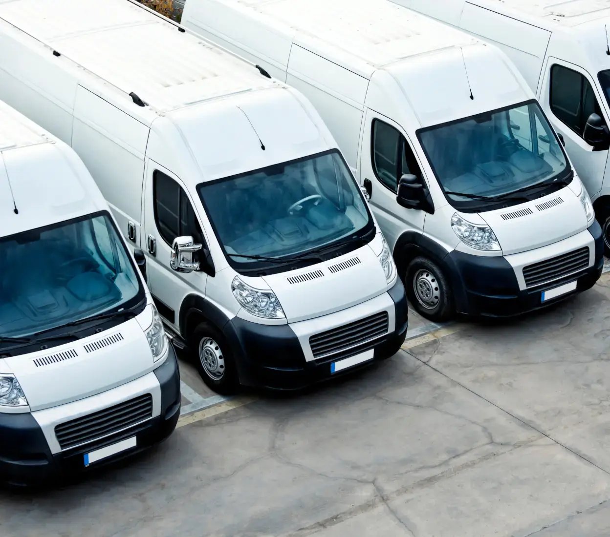 A row of white vans in a parking lot