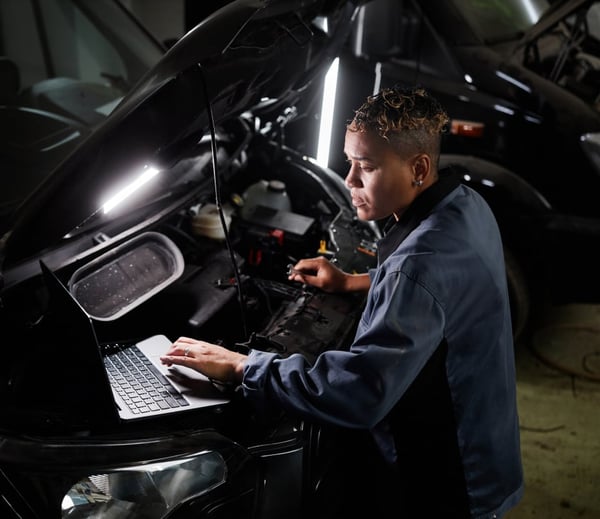 Mechanic in dark blue overalls working on a van engine