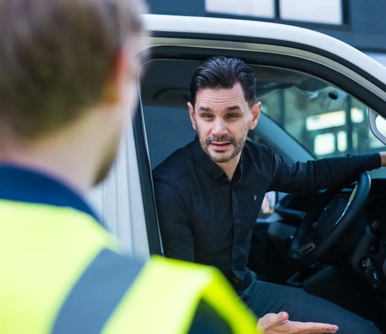 person sat in van with door open talking to another person