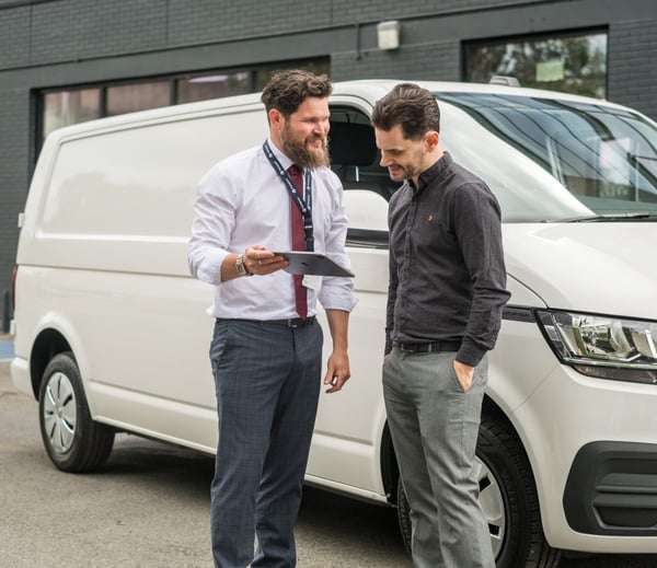 Transpoco employee standing in front of a white van, showing a driver data on a tablet