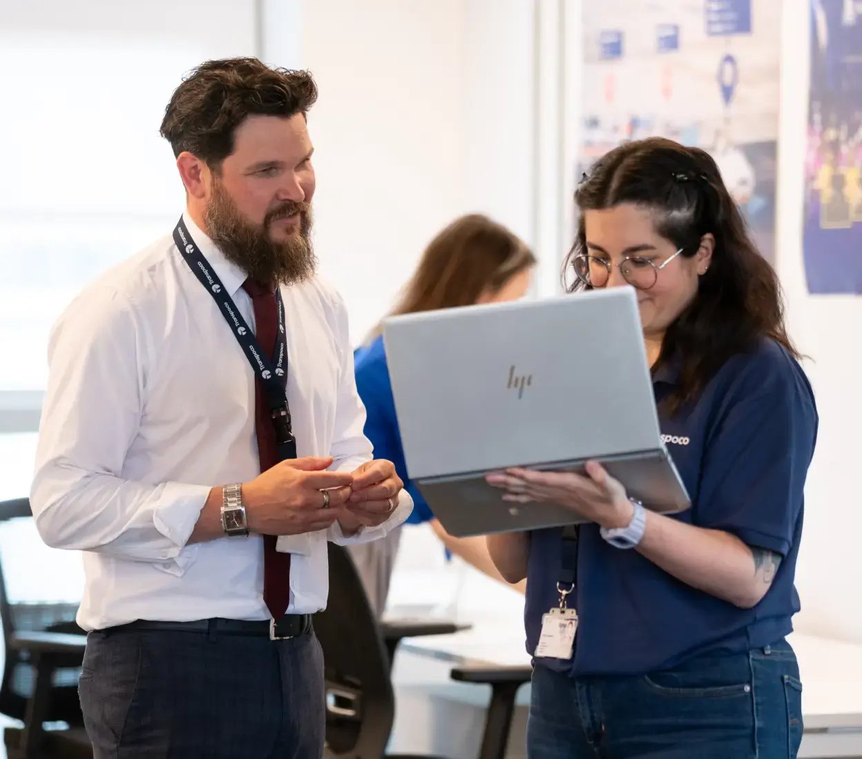 Two Transpoco employees standing in an office, reviewing data on a laptop