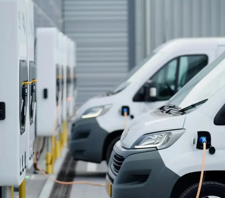 Two white vans, side-by-side, plugged in to electric charging points